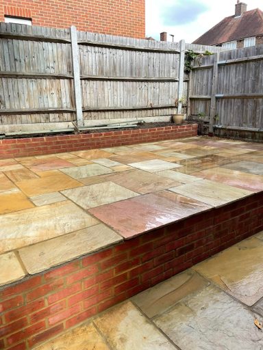 Sturdy brick wall topped with a sandstone patio, offering a stylish outdoor area for lounging