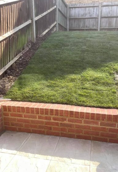 Brick wall acting as a retaining structure for a sloped lawn, showcasing effective landscaping