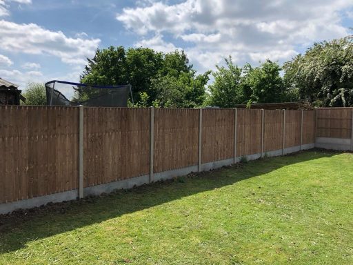 Sturdy closed board fence with concrete posts marking the boundary of a garden